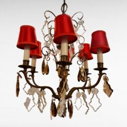 Taklampa i mässing med bruna glasprismor, röda skärmar. Stearinljusliknande lamphållare.