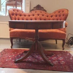 Runt brunt bord med lådor, grön skiva och lejontassar.